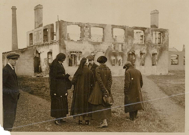 Photograph of Maud Gonne MacBride, Charlotte Despard and Dorothy Macardle as they inspect the burnt-out ruins of a hosiery factory in Balbriggan during the War of Independence in 1920. Dorothy Macardle is wearing a beret and is holding a bag behind her back. Photograph by W.D. Hogan and published in the ‘American Commission on Conditions in Ireland Interim Report,’ 1920. Image courtesy of Kilmainham Gaol Museum/OPW and ©National Museum of Ireland